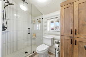 Full bathroom featuring a shower stall, a textured ceiling, and wood finished floors