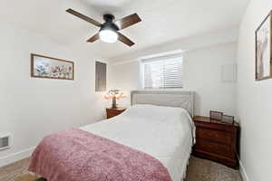 Bedroom with dark colored carpet, ceiling fan, electric panel, and a textured ceiling
