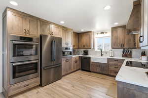 Kitchen with stainless steel appliances, light stone countertops, light wood finished floors, backsplash, and recessed lighting