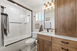 Full bath featuring vanity and bath / shower combo with glass door
