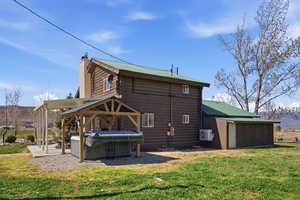 Back of property featuring a metal roof, a lawn, a hot tub, a chimney, and log siding