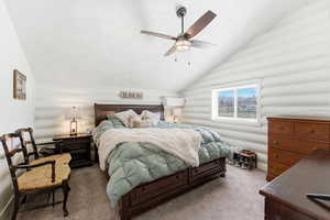 Bedroom featuring vaulted ceiling, log walls, carpet floors, and ceiling fan