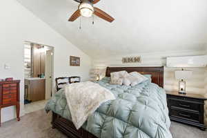 Bedroom featuring vaulted ceiling, a ceiling fan, light carpet, and ensuite bathroom