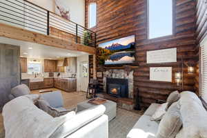 Living area with a high ceiling, log walls, and light wood finished floors