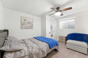 Carpeted bedroom featuring a textured ceiling and ceiling fan