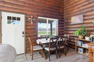 Dining area with log walls and wood finished floors