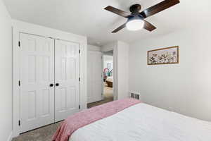 Carpeted bedroom featuring ceiling fan and a closet