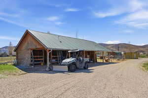 View of front facade featuring an outdoor structure, a metal roof, log siding, a mountain view, and an exterior structure