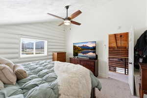 Carpeted bedroom with vaulted ceiling, log walls, and a ceiling fan