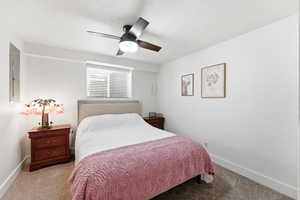 Carpeted bedroom featuring ceiling fan, electric panel, and a textured ceiling