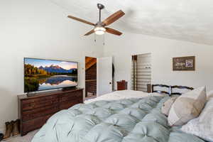 Bedroom with vaulted ceiling, ceiling fan, and carpet flooring