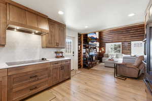 Kitchen featuring rustic walls, open floor plan, wood finish cabinetry, light wood-type flooring, and recessed lighting
