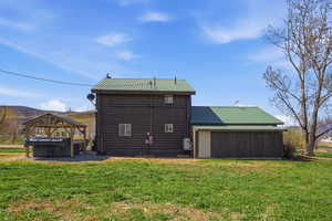 Rear view of property featuring a metal roof, a gazebo, a lawn, and a mountain view
