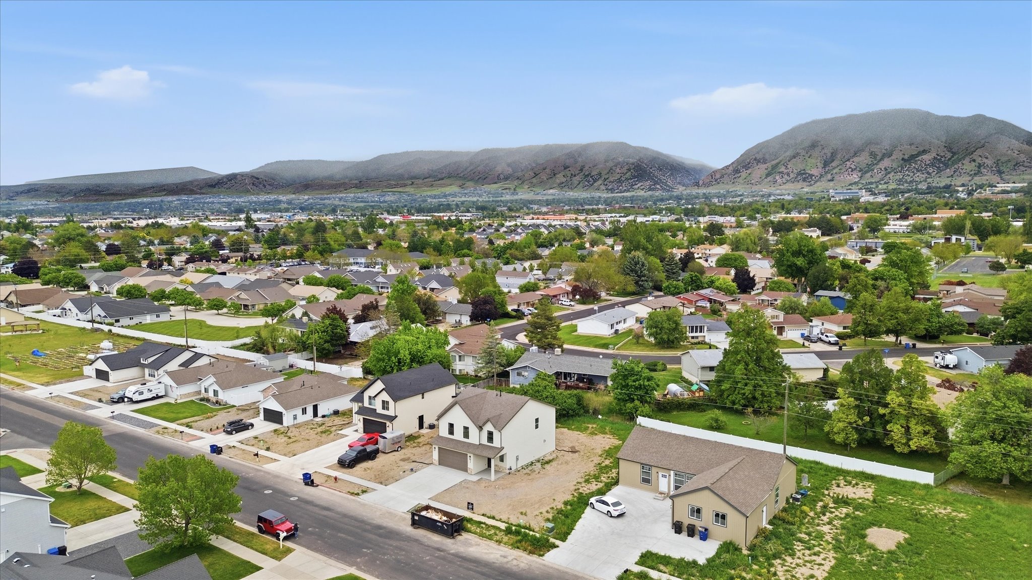 Expansive residential landscape featuring a mix of established and developing properties, framed by distant mountains