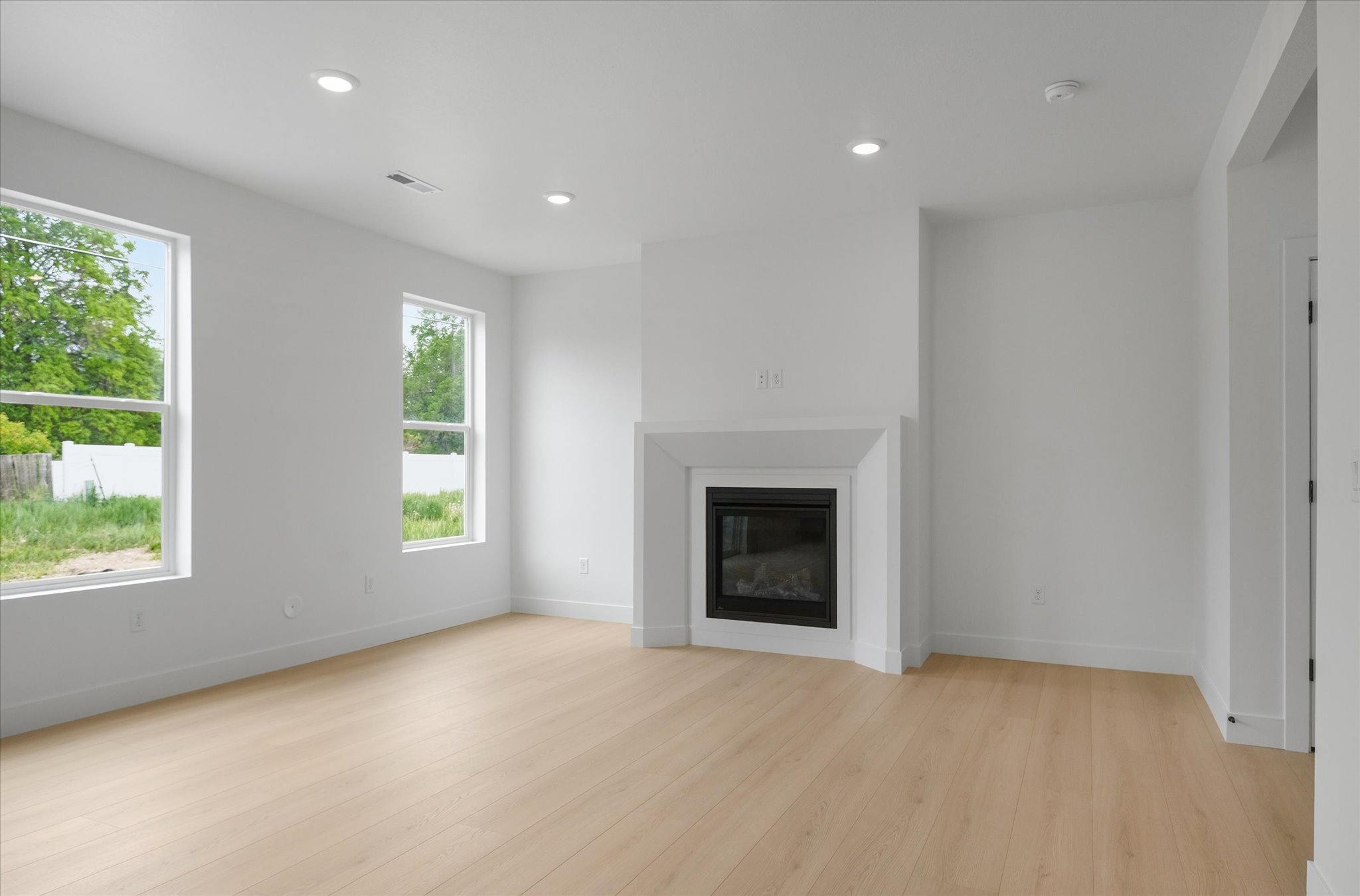 Living space featuring light wood-finish flooring, recessed lighting, and a contemporary fireplace with a clean-lined mantel