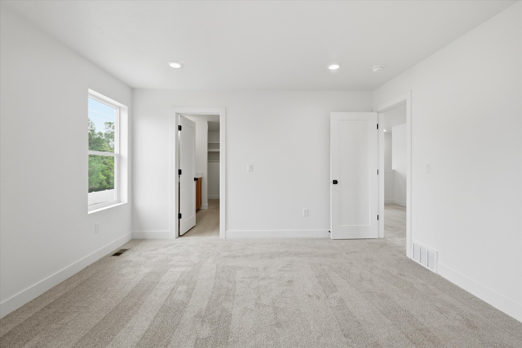 Spacious room featuring light gray carpeting and white walls