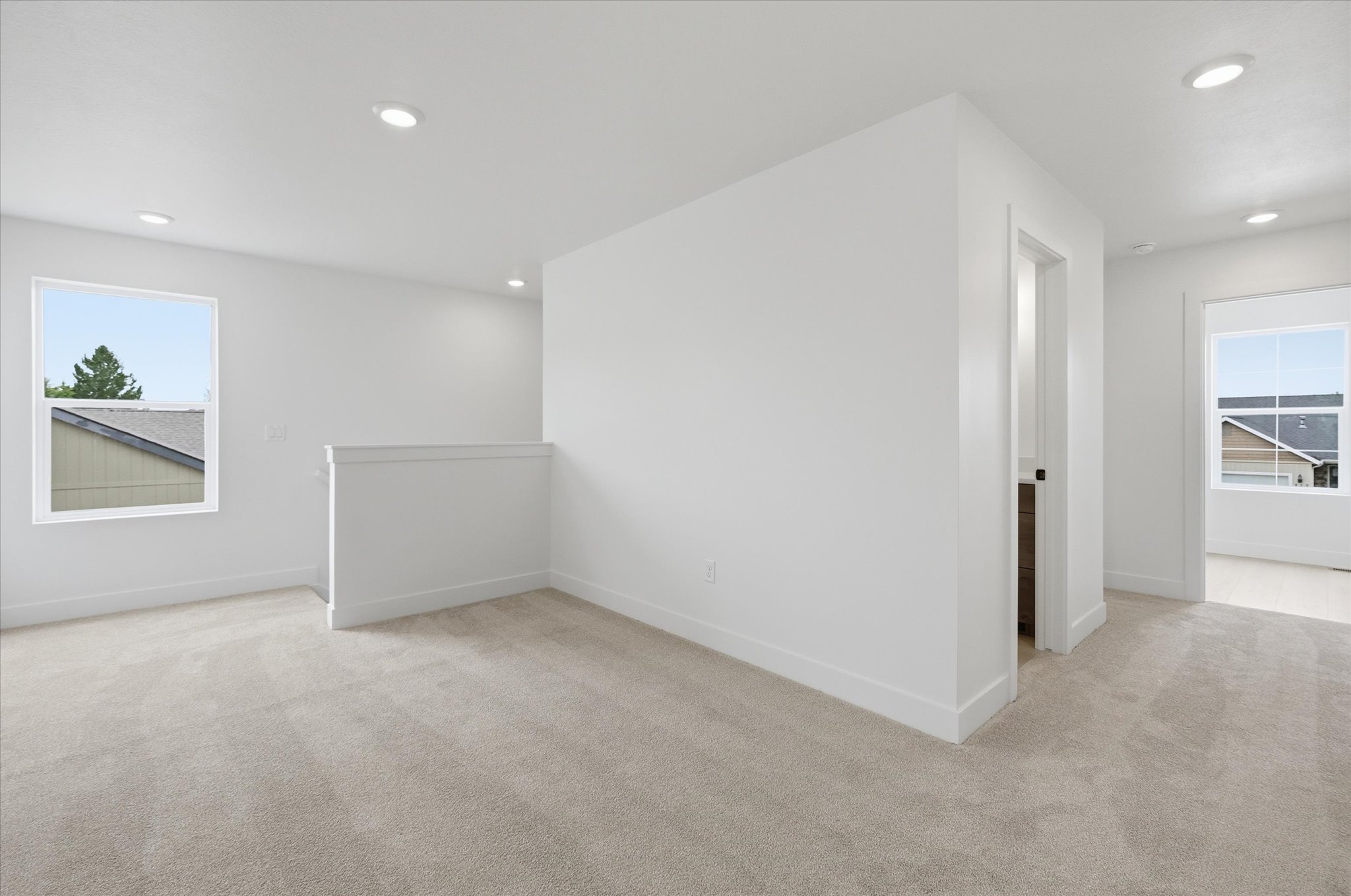 Expansive carpeted area featuring recessed lighting, multiple windows, and crisp white walls