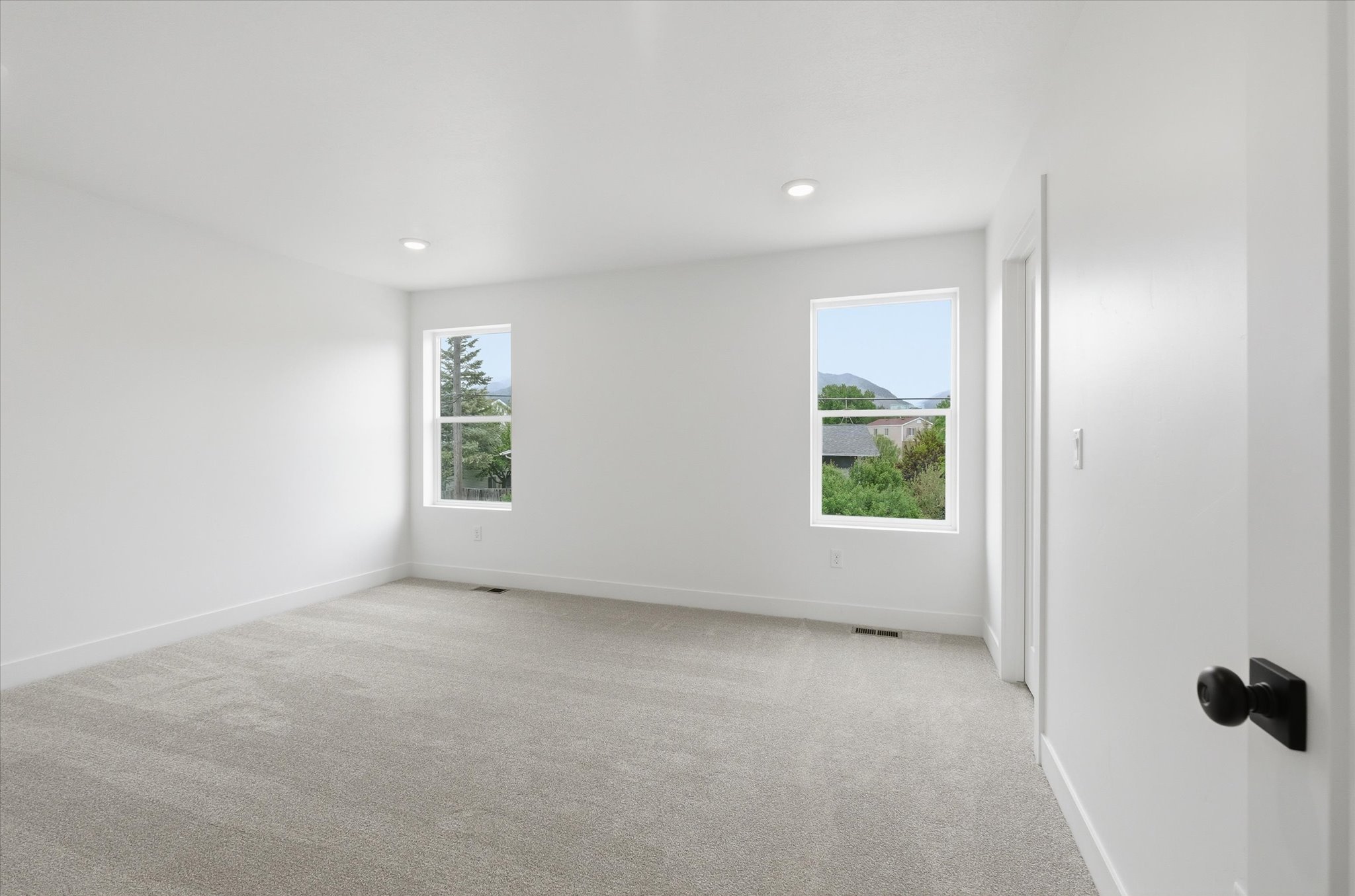 Bright room featuring two windows, recessed lighting, neutral carpeting, and white walls