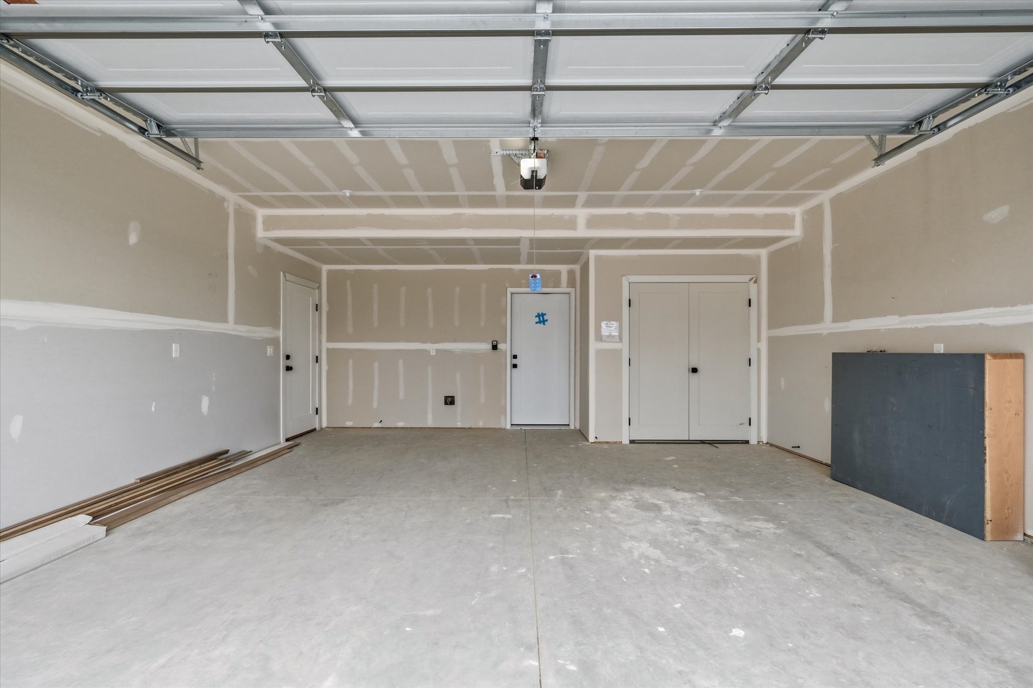 Spacious garage featuring a concrete floor, two entry doors, and a double-door closet