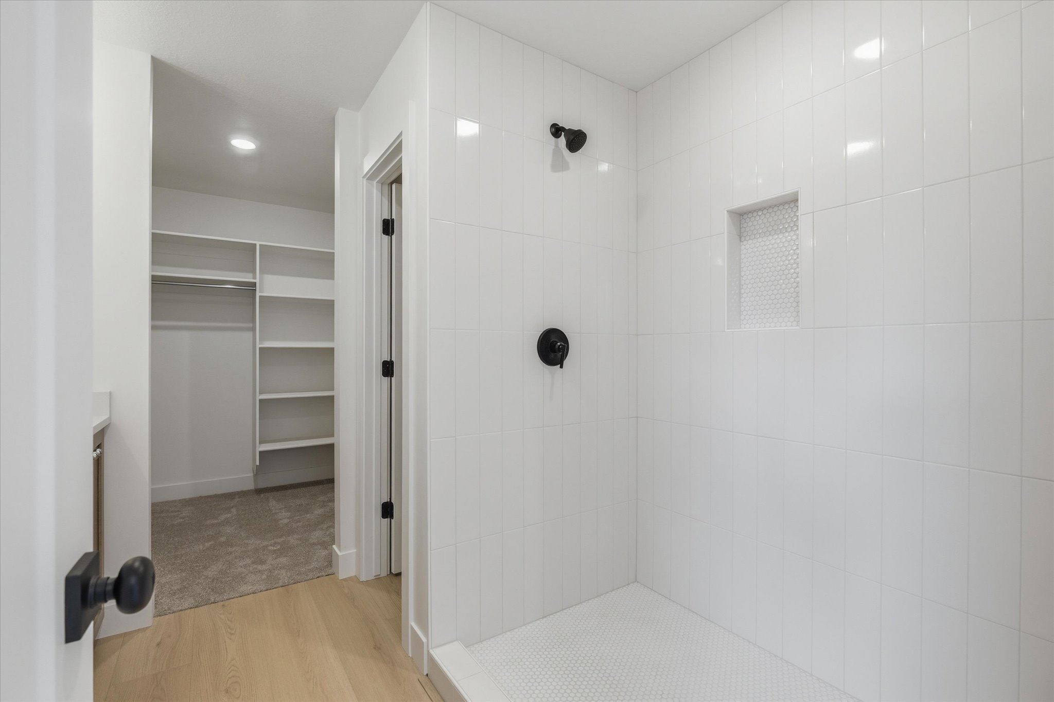 Walk-in shower with vertical subway tile, integrated niche, and matte black fixtures
