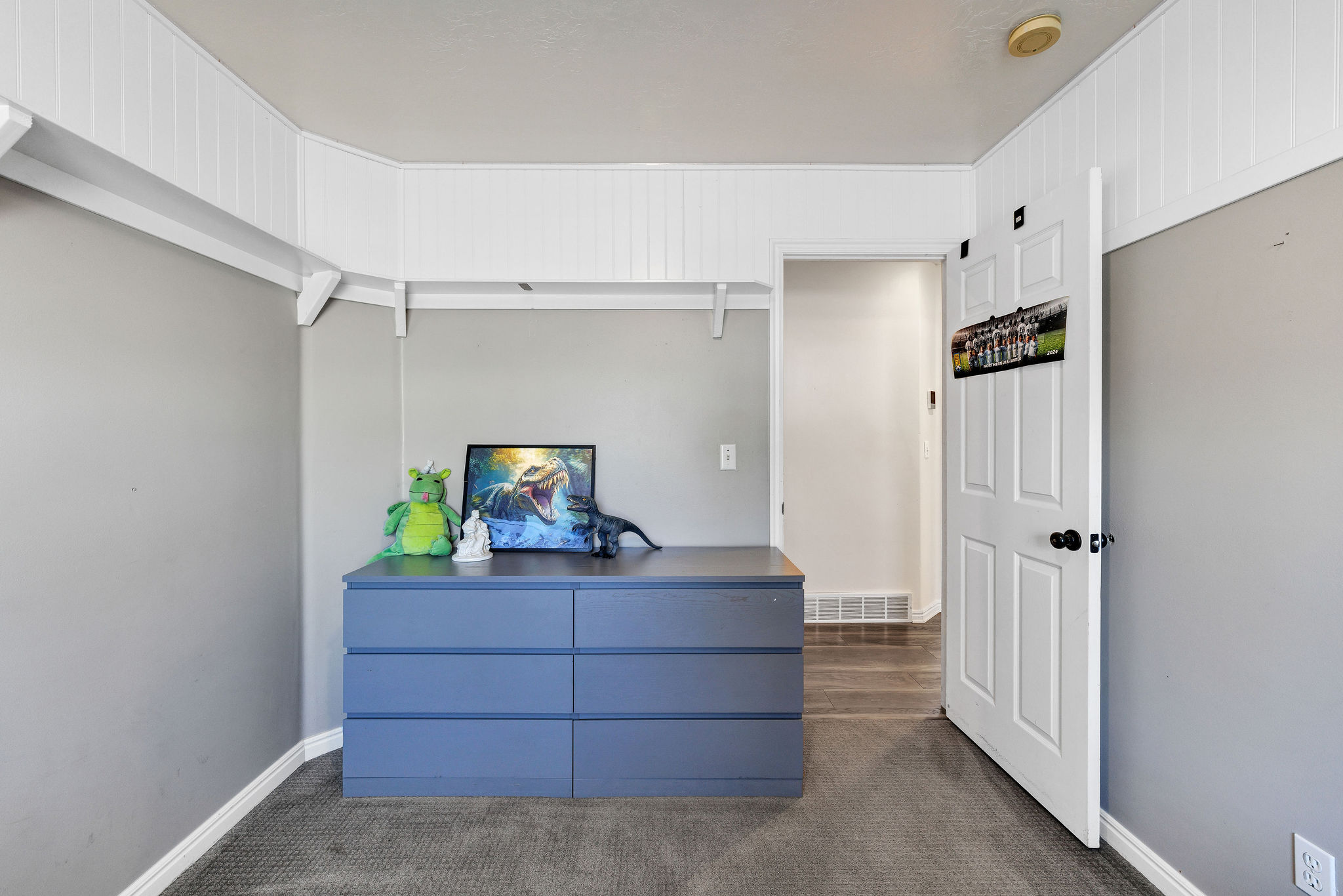 Bedroom with dark colored carpet and shelving around