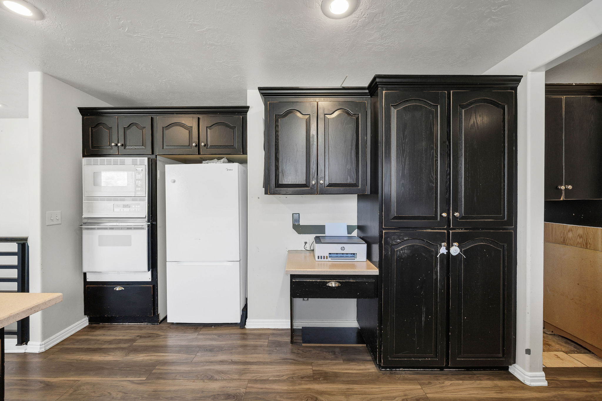 Kitchen featuring white appliances, dark wood-style flooring, and dark cabinetry