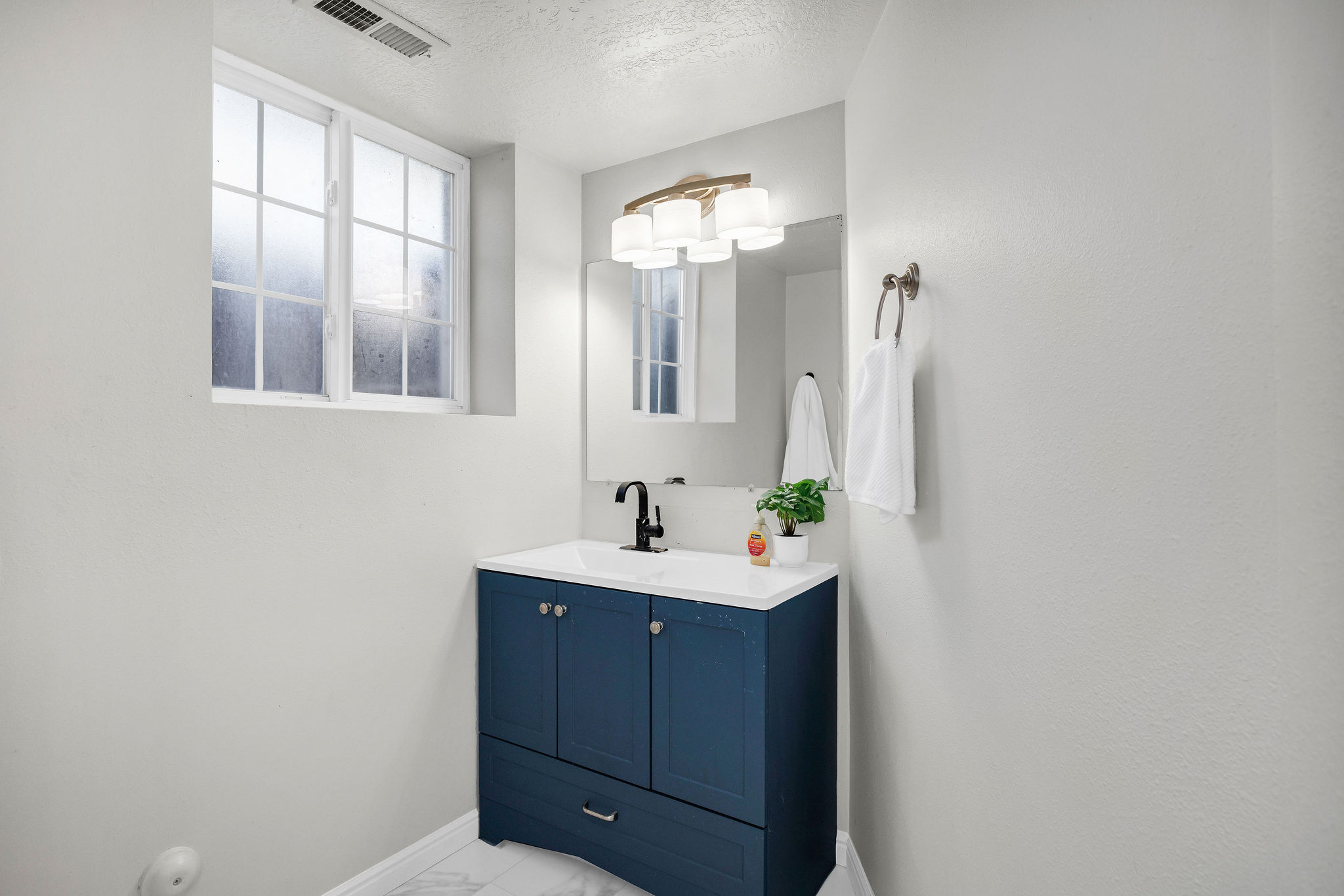 Bathroom fin basement eaturing a textured ceiling, vanity, and light marble finish floors