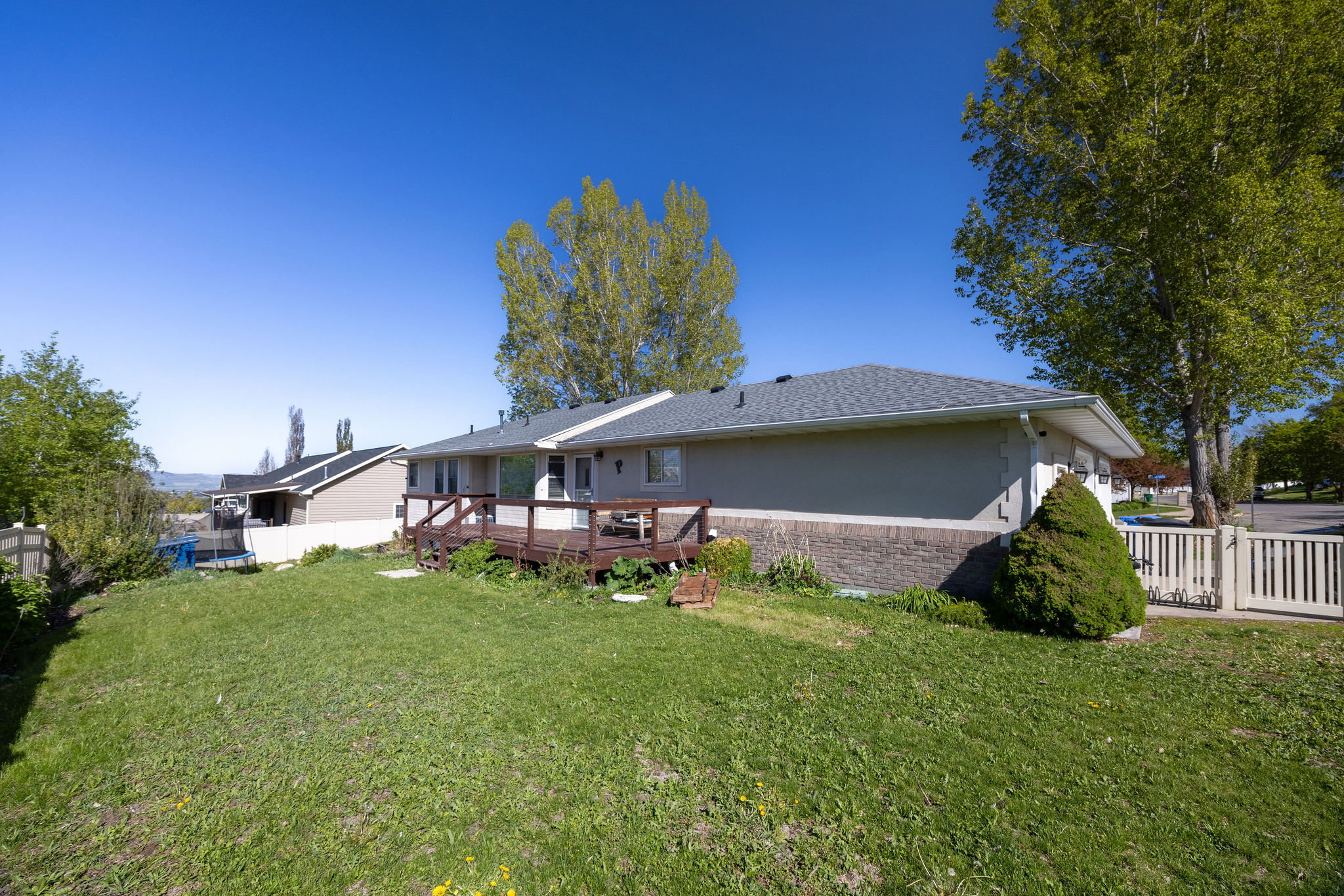 Rear view of house featuring brick siding, a wooden deck, and roof with shingles