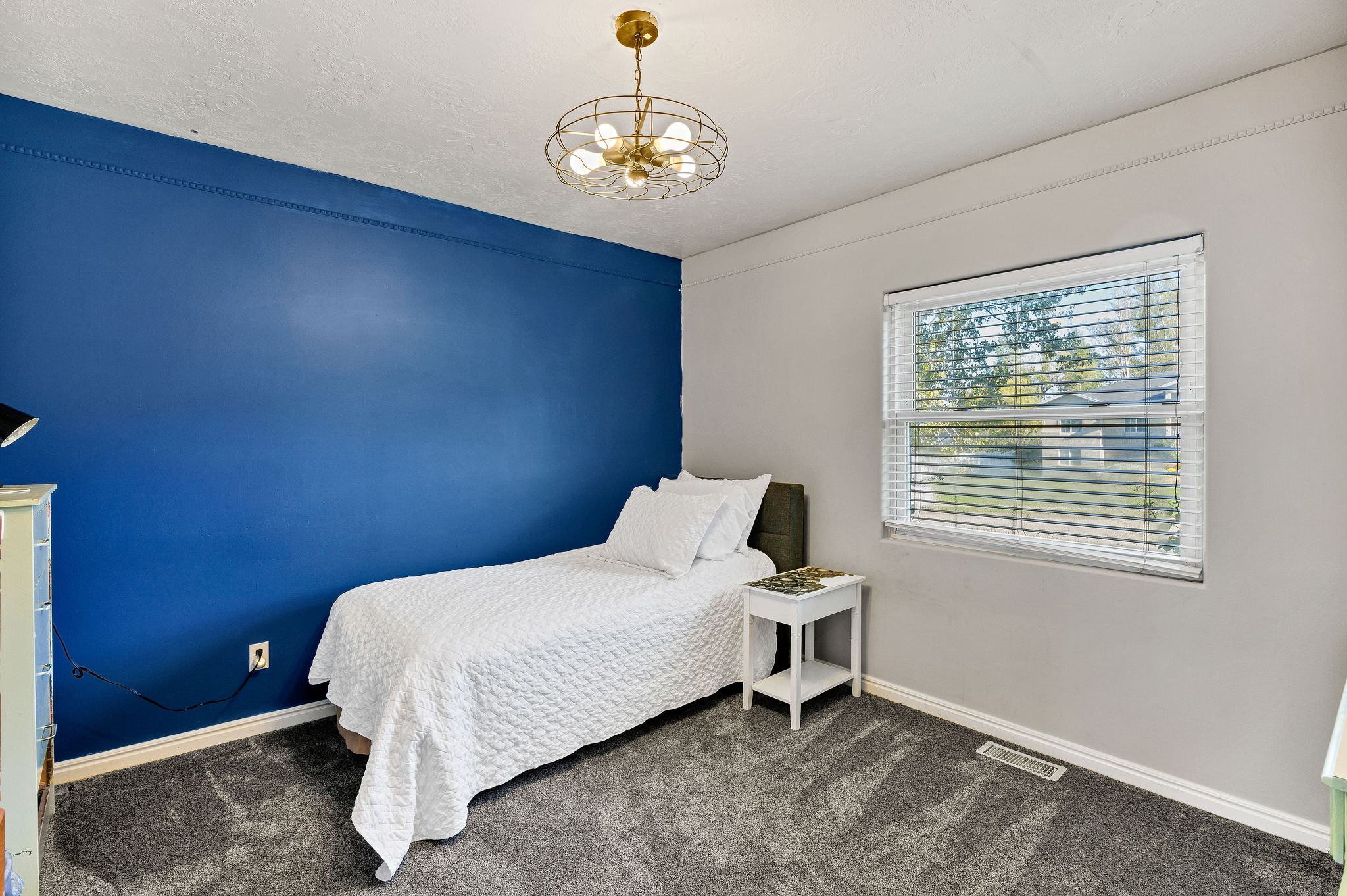 Bedroom featuring suspended lighting and dark carpet