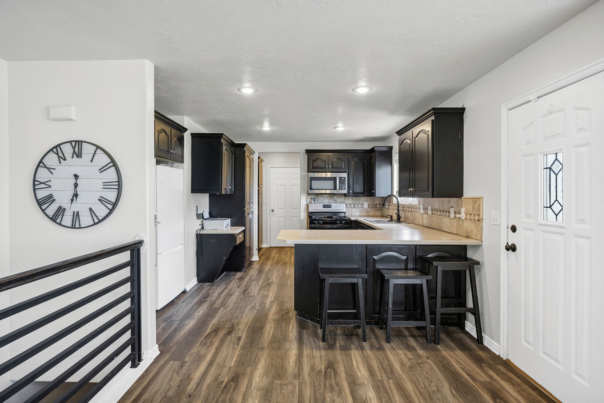 Kitchen featuring light countertops, a breakfast bar area, a peninsula, stainless steel appliances, and dark wood finished floors