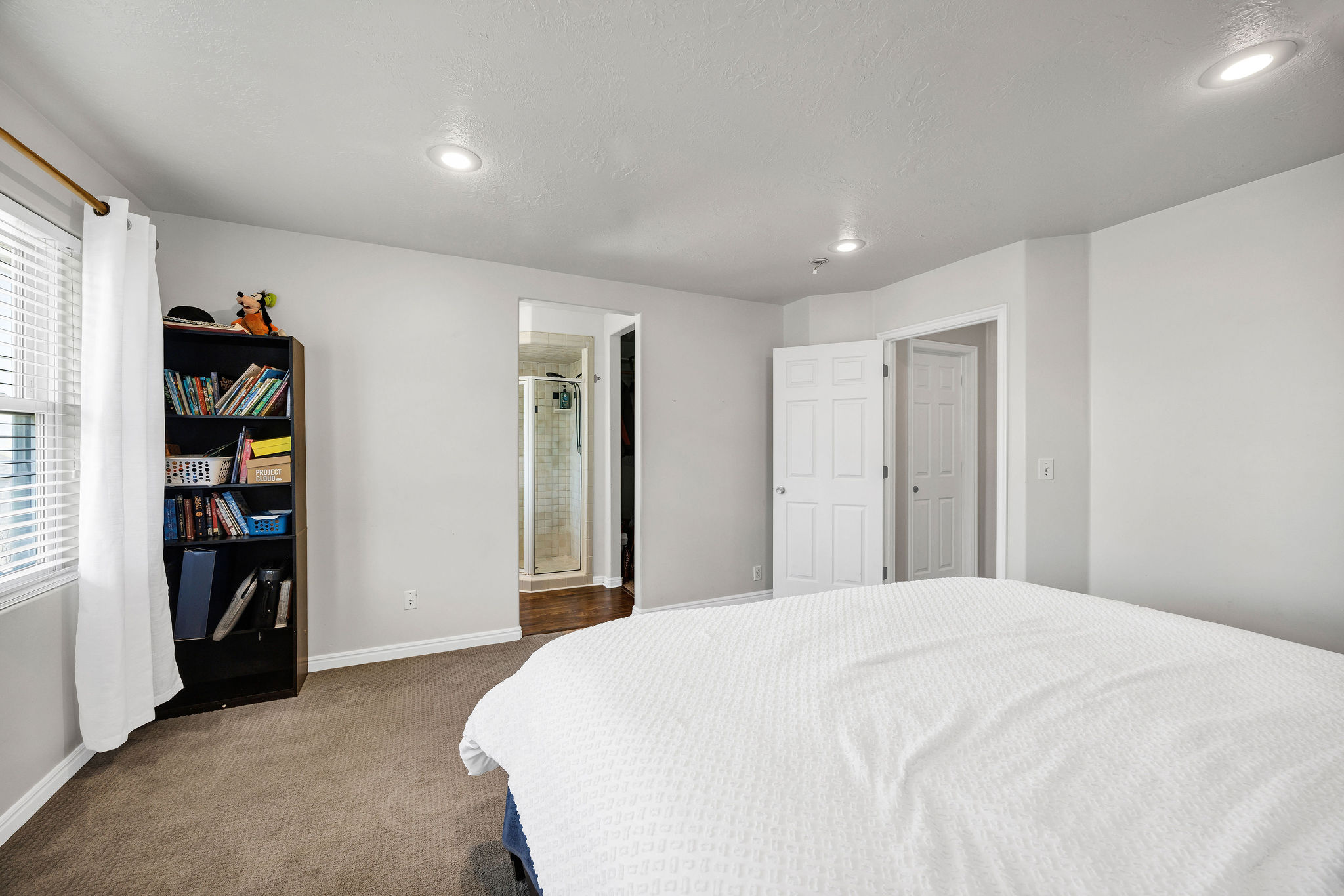 Primary Bedroom with dark colored carpet, ensuite bath, and recessed lighting