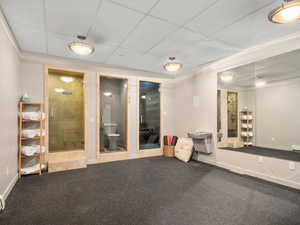 Carpeted empty room featuring a drop ceiling and a relaxing sauna