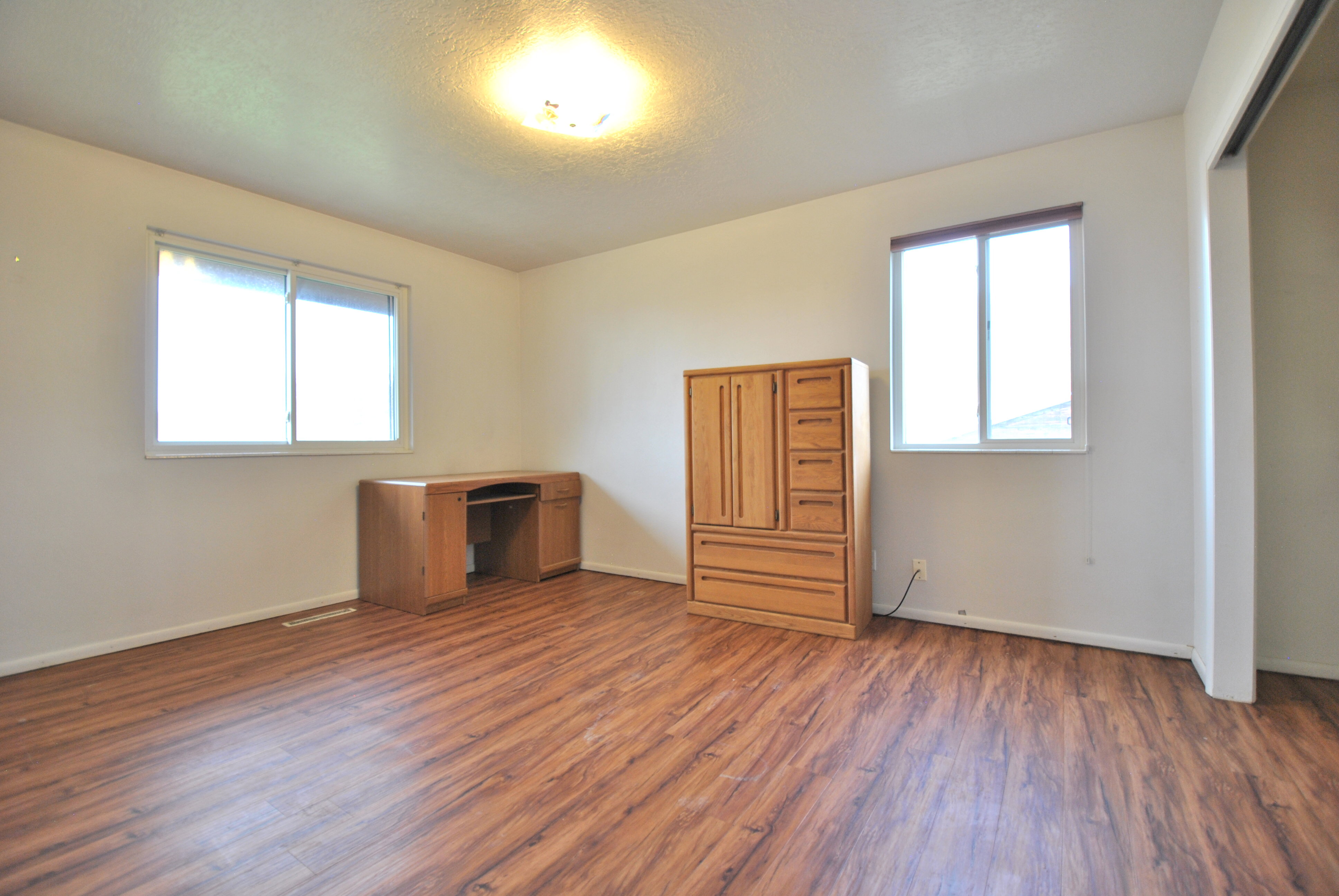 Unfurnished bedroom with dark wood-style floors, a textured ceiling, and an office area