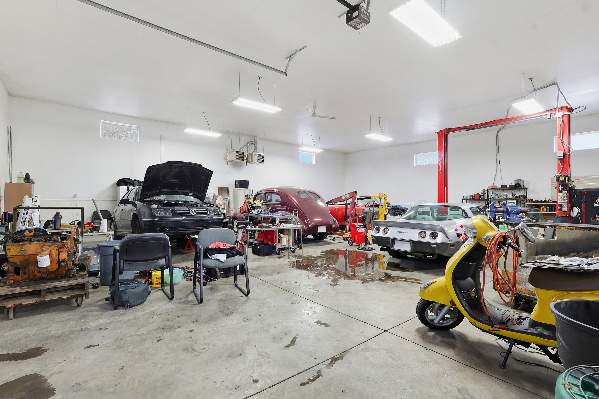 Spacious garage interior featuring high ceilings with recessed and suspended lighting