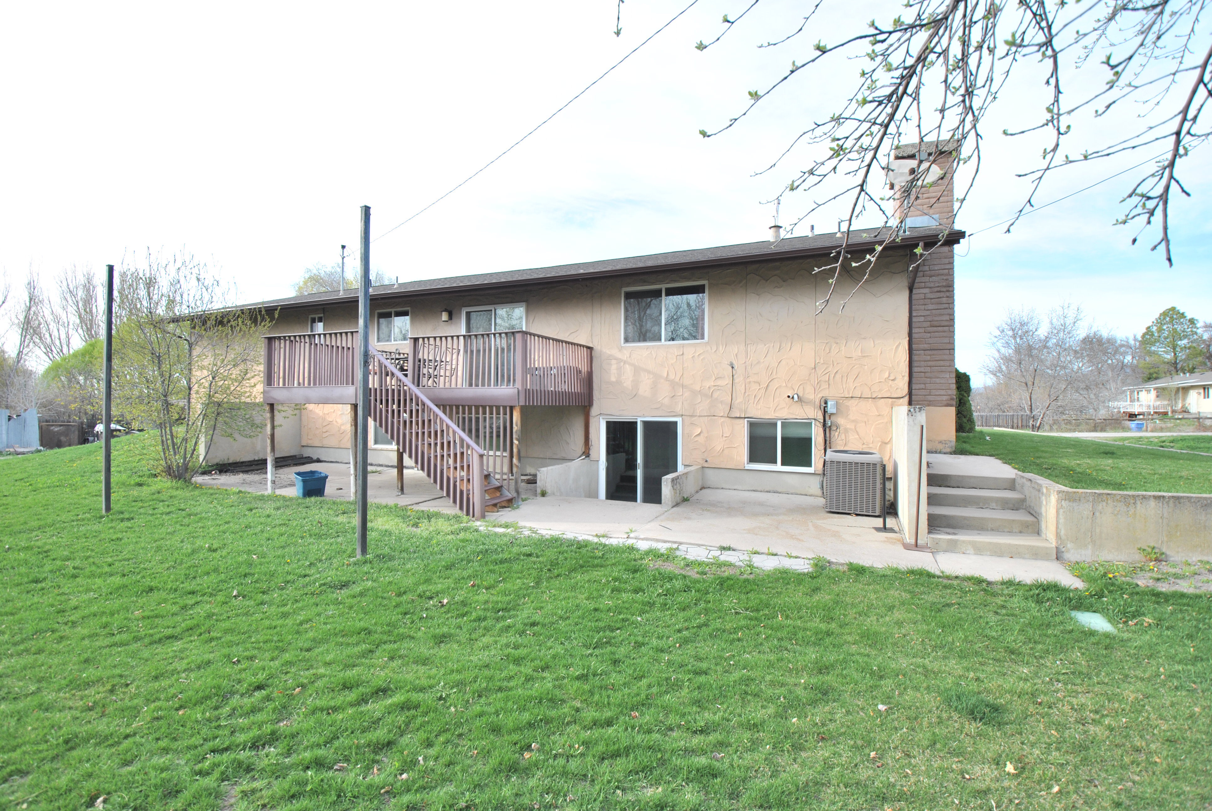 Back of house featuring a patio, a lawn, a chimney, and stucco siding