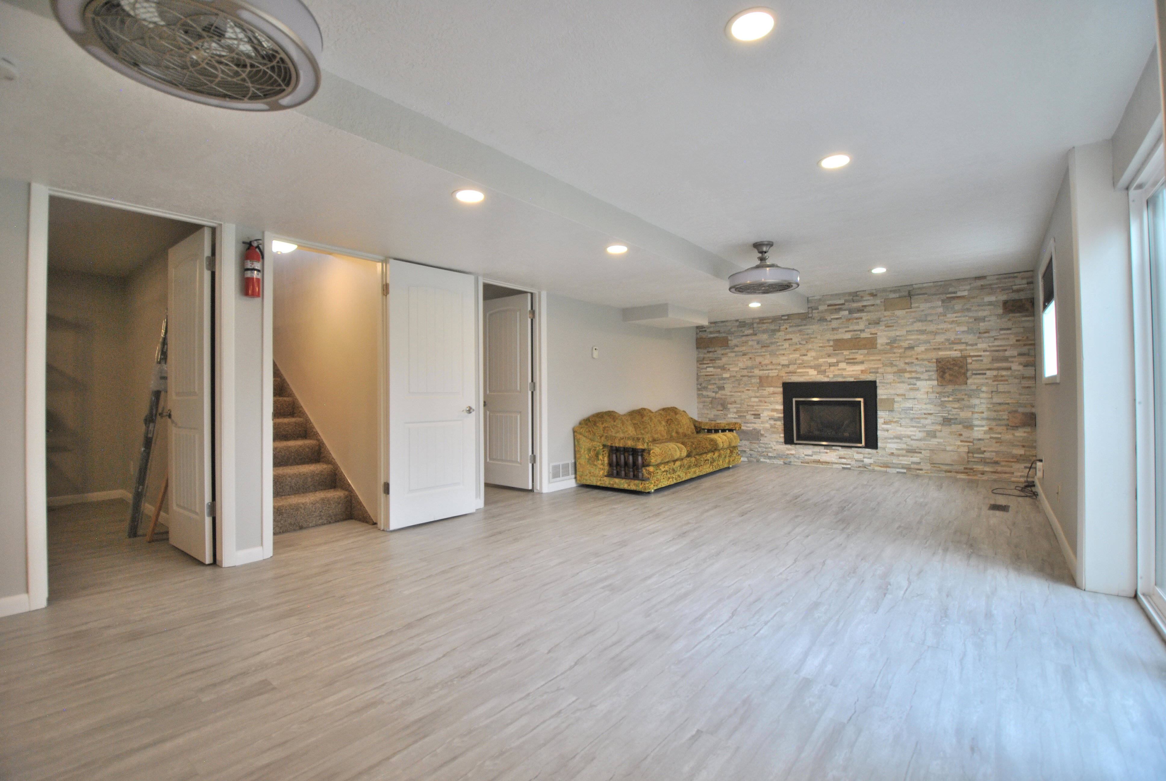 Recreation  room with a stone fireplace, recessed lighting, and light wood-style flooring