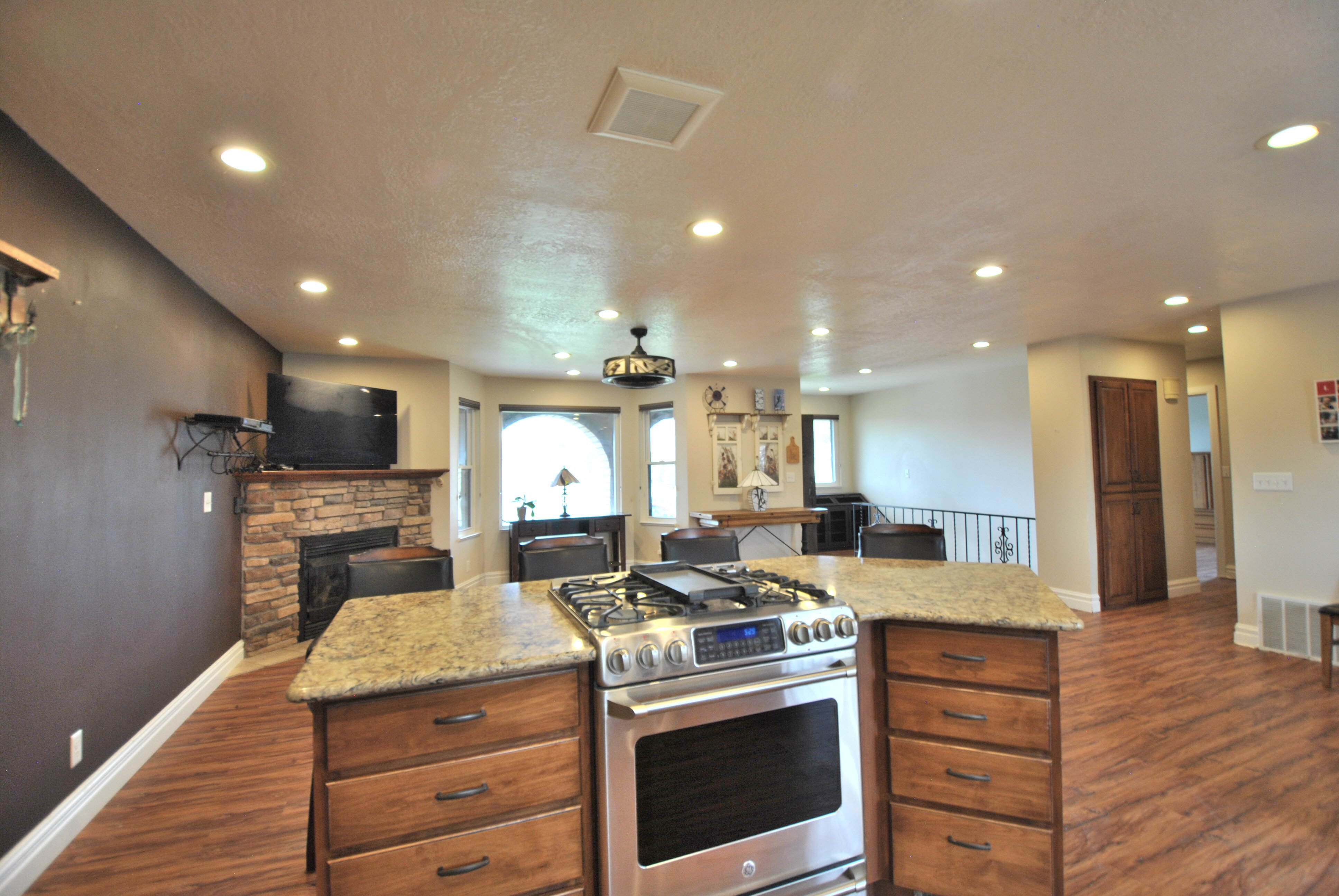 Kitchen featuring open floor plan, stainless steel gas range oven, light stone countertops, dark wood-style floors, and recessed lighting
