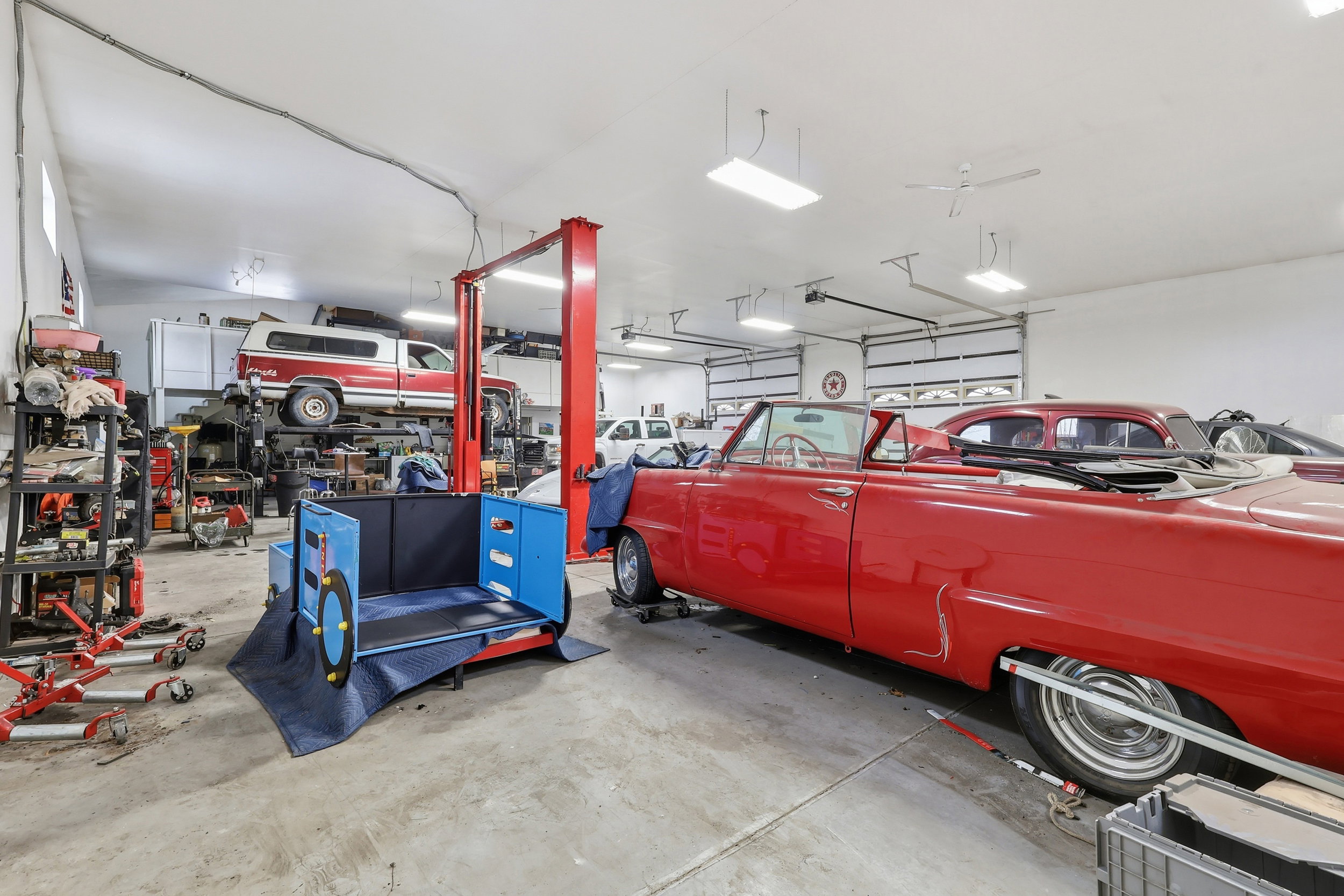 Spacious garage with multiple overhead doors, concrete flooring, and ample overhead lighting
