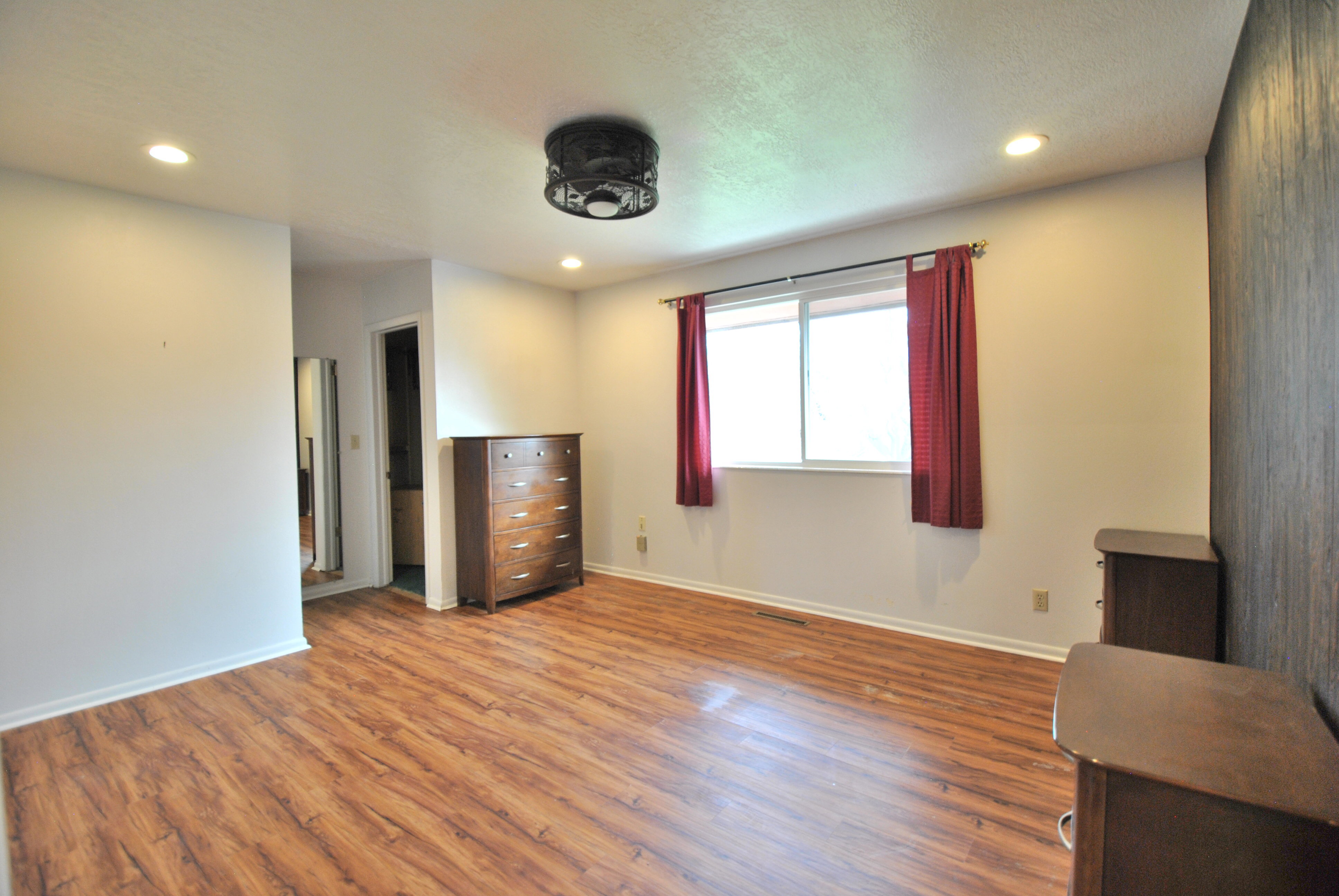 Bedroom with wood finished floors and recessed lighting, ensuite bathroom, and walk in closet.