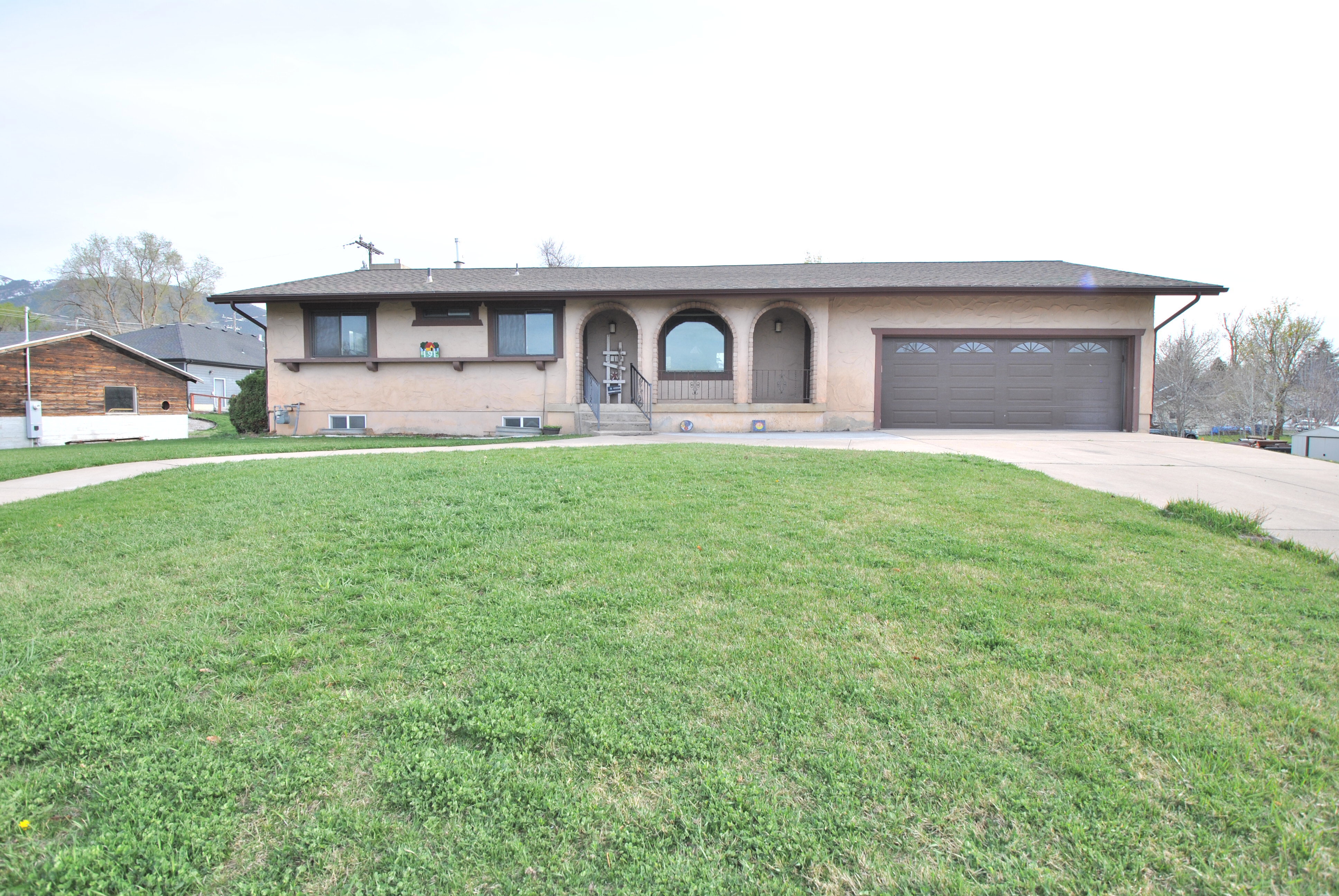 Ranch-style house featuring a front yard, driveway, a garage, and stucco siding