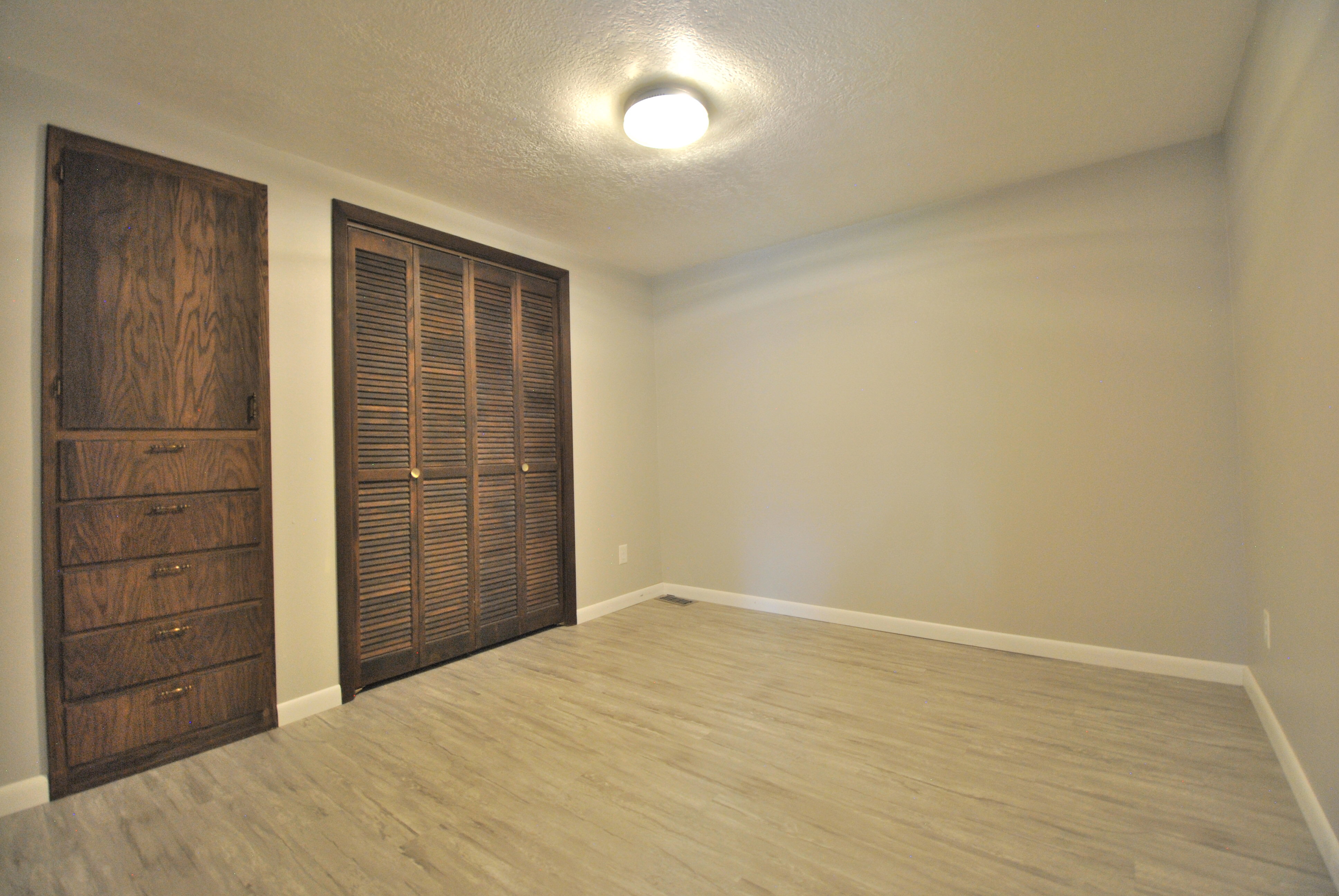 Storage room with a textured ceiling, light wood-style floors, and a closet