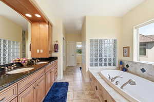 Full bath with double vanity, recessed lighting, a garden tub, and light tile patterned floors