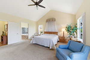 Bedroom featuring light colored carpet, ceiling fan, a high ceiling, and connected bathroom