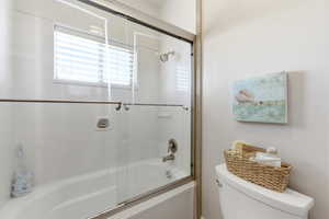 Bathroom featuring toilet and combined bath / shower with glass door