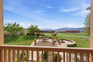 Wooden deck featuring a fire pit, a patio, a yard, and a mountain view