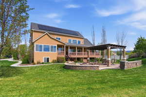 Back of property featuring roof mounted solar panels, a patio, a lawn, and stucco siding