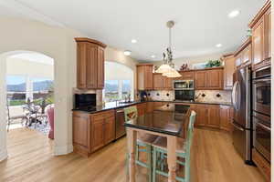 Kitchen featuring wood finish cabinets, arched walkways, dark stone countertops, and stainless steel appliances