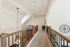 Hall with beamed ceiling and light colored carpet