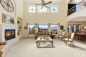 Living area with arched walkways, ornamental molding, a mountain view, a glass covered fireplace, and carpet floors