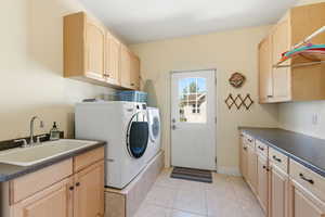 Laundry room with cabinet space, light tile patterned floors, and washing machine and clothes dryer